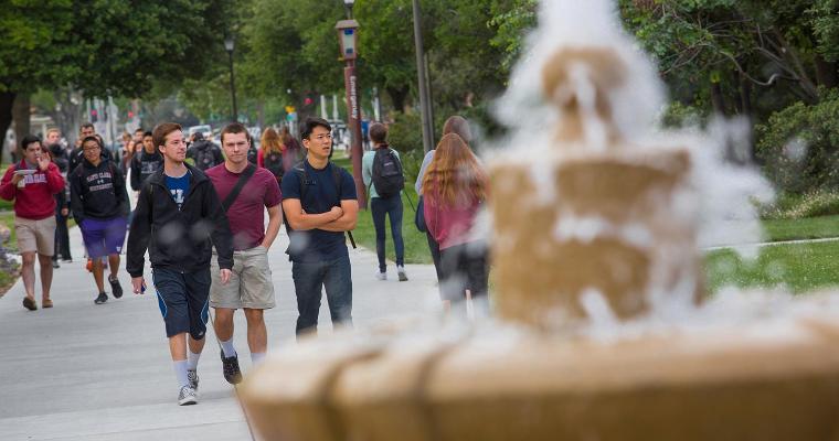 Students walking behind the fountain on Abby Sobrato Mall. 