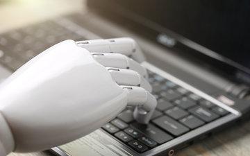 robot hand typing on a computer image link to story