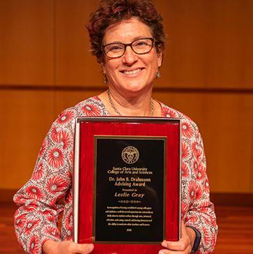Leslie Grey holding award plaque image link to story