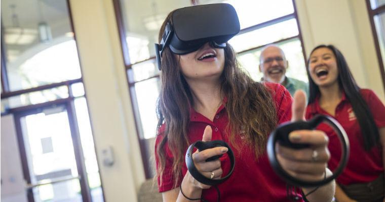 An SCU student with a virtual reality headset and hand controls. image link to story