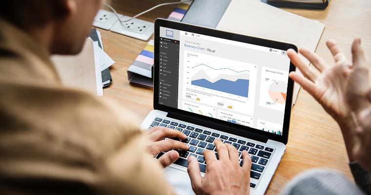 Two people collaborating in front of a laptop with business analytics on the screen. 