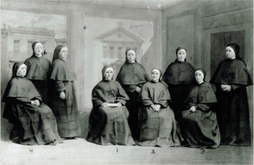 Nine women wearing dark habits pose for a portrait